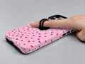 Tiny Red Hearts MagSafe Loop iPhone Case shown in use with a finger through the horizontal loop