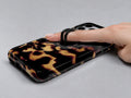 Tortoiseshell MagSafe Loop iPhone Case shown in use with a finger through the horizontal loop