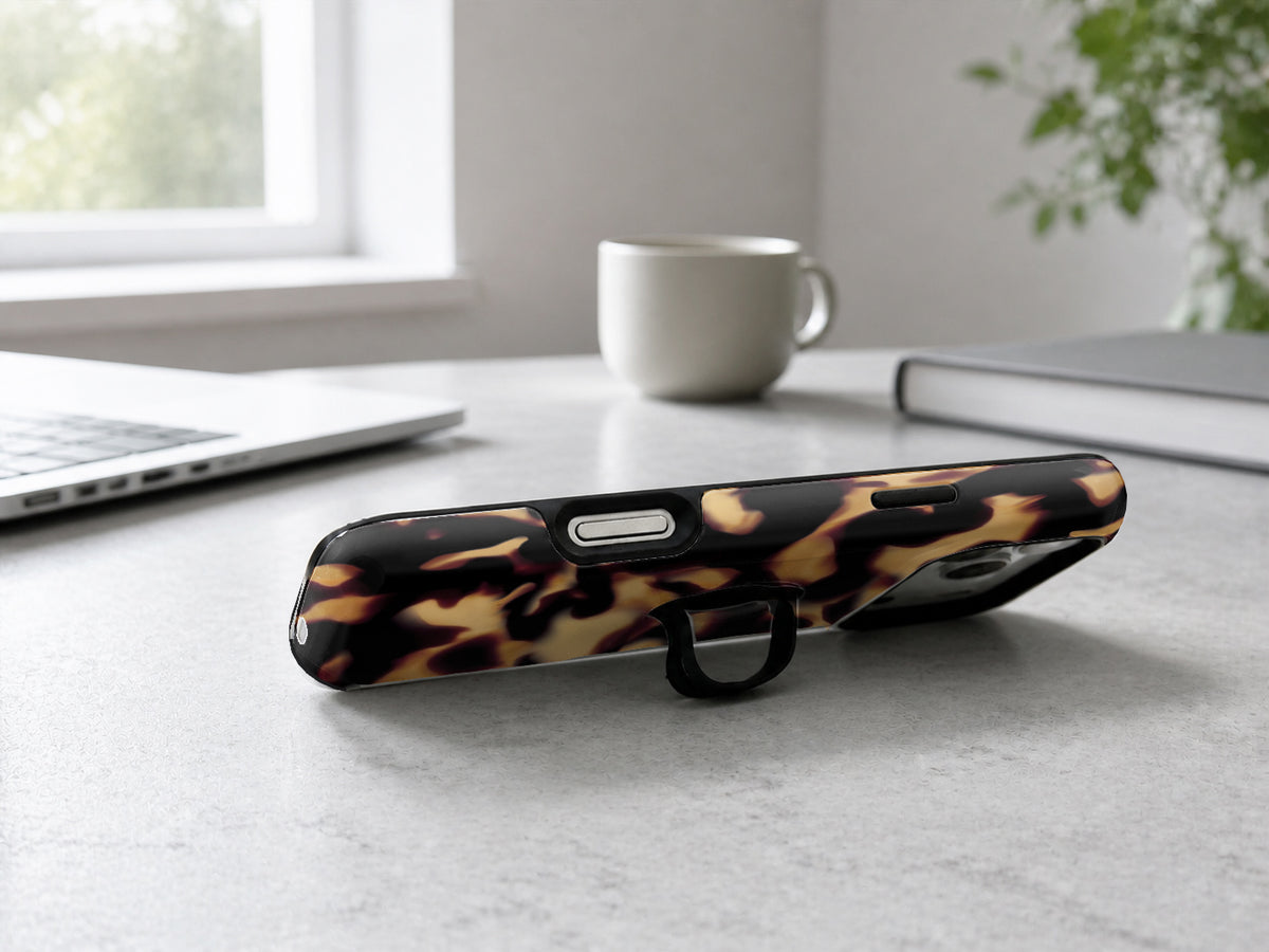 Tortoiseshell MagSafe Loop iPhone Case shown in a neutral white professional lifestyle setting