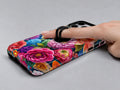 Vibrant Garden Floral Bouquet MagSafe Loop iPhone Case shown in use with a finger through the horizontal loop