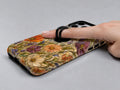 Vintage Autumn Wildflower MagSafe Loop iPhone Case shown in use with a finger through the horizontal loop