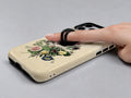 Vintage Botanical Bouquet MagSafe Loop iPhone Case shown in use with a finger through the horizontal loop