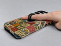 Vintage Folk Tile Patchwork MagSafe Loop iPhone Case shown in use with a finger through the horizontal loop