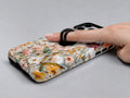 Warm Wildflower Stained Glass MagSafe Loop iPhone Case shown in use with a finger through the horizontal loop